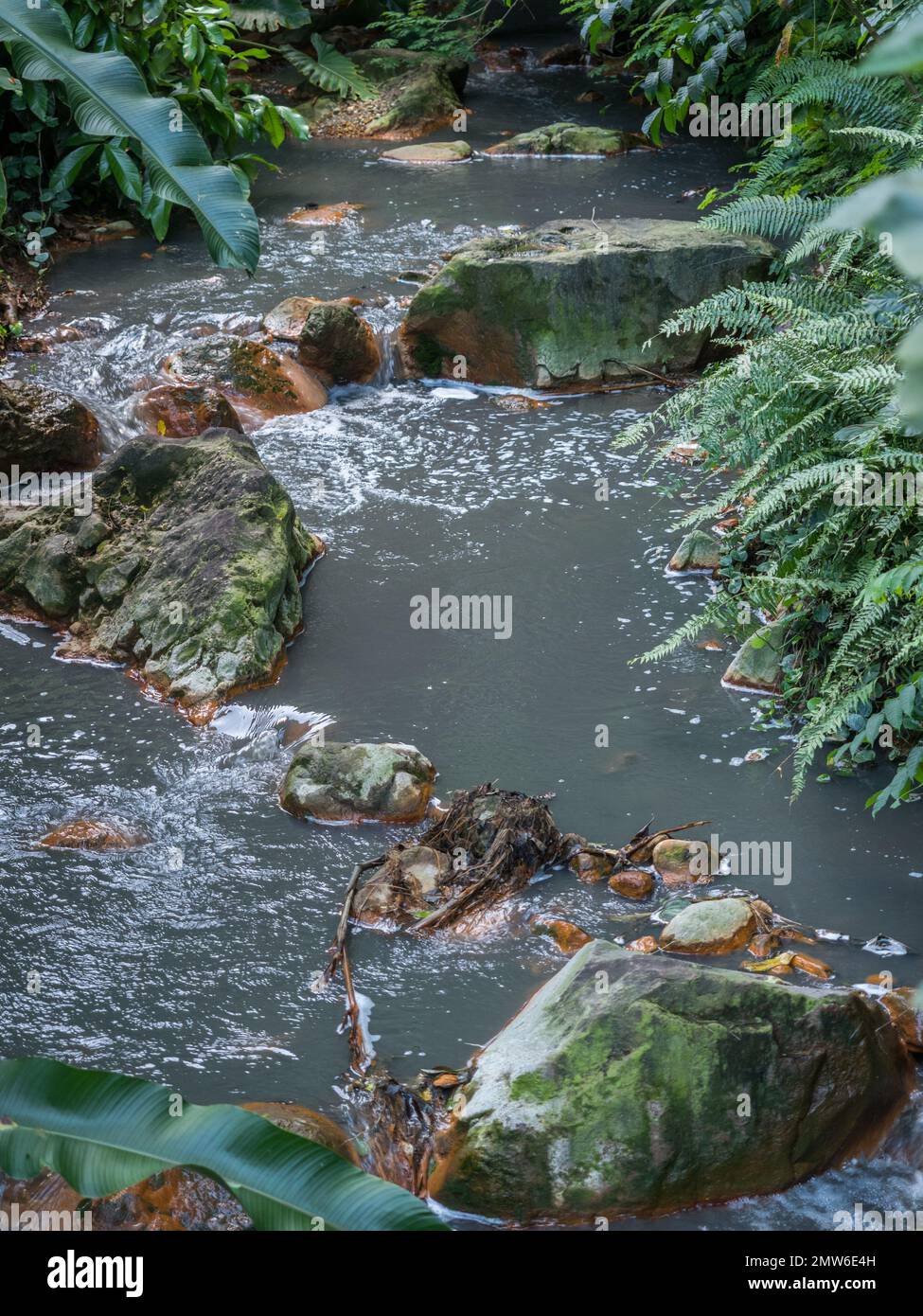 un tiro stretto di acqua corrente che scorre curvando rocce rotonde verso la fotocamera Foto Stock