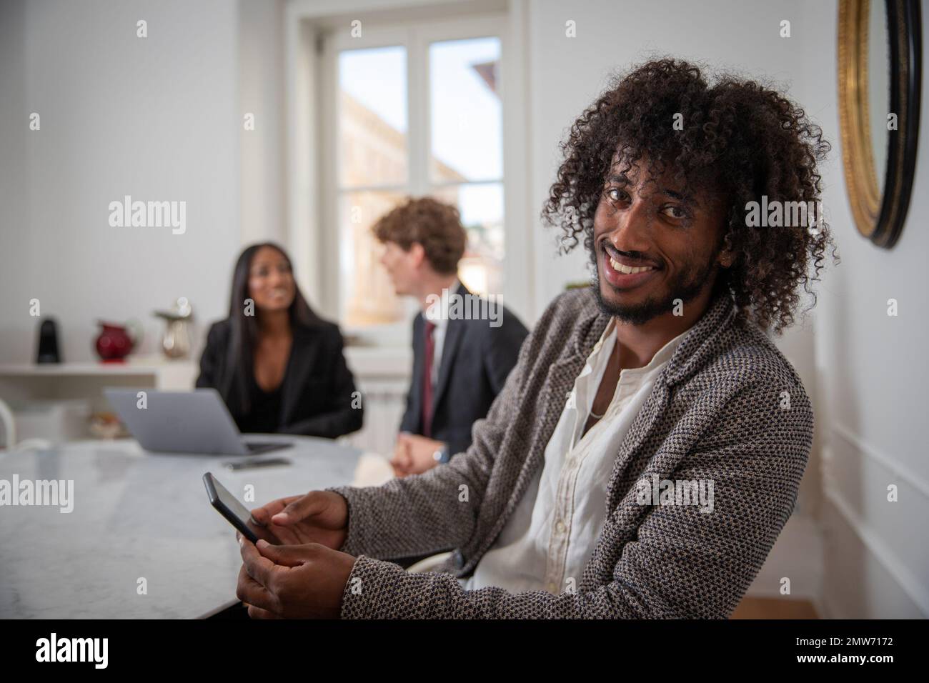 Un gruppo di giovani imprenditori durante un incontro, primo piano sul giovane imprenditore africano sorridente Foto Stock
