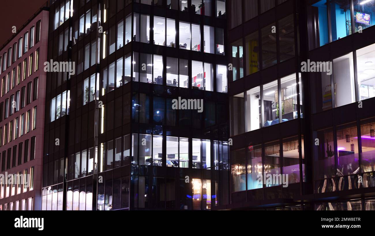 Edificio aziendale di notte - concetto di affari. Edificio di uffici con pareti di vetro. Moderne finestre da ufficio di grattacielo che si illuminano di notte. Foto Stock