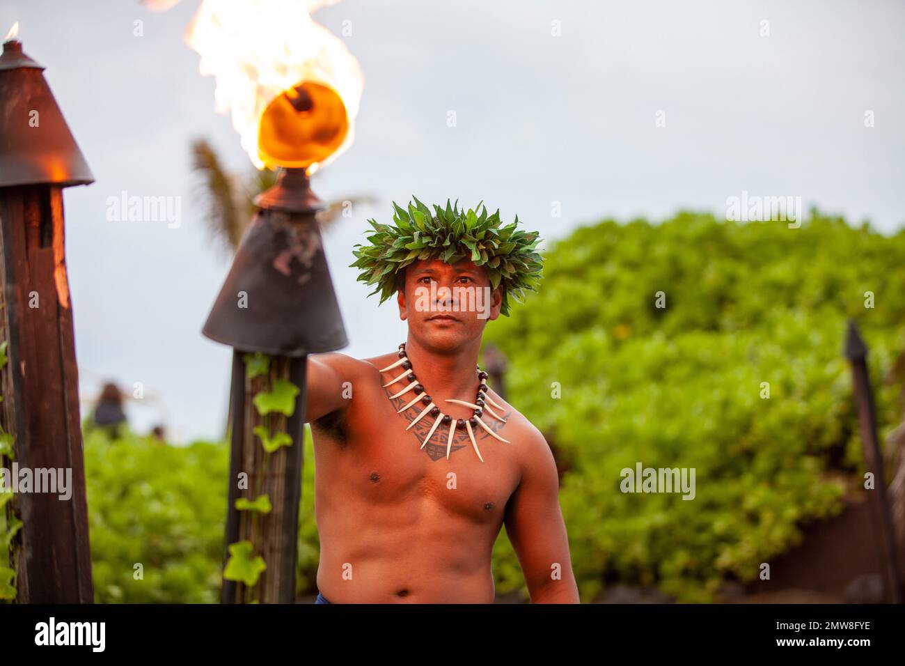 Uomo hawaiano in abito tradizionale che illumina una torcia prima dello spettacolo Foto Stock