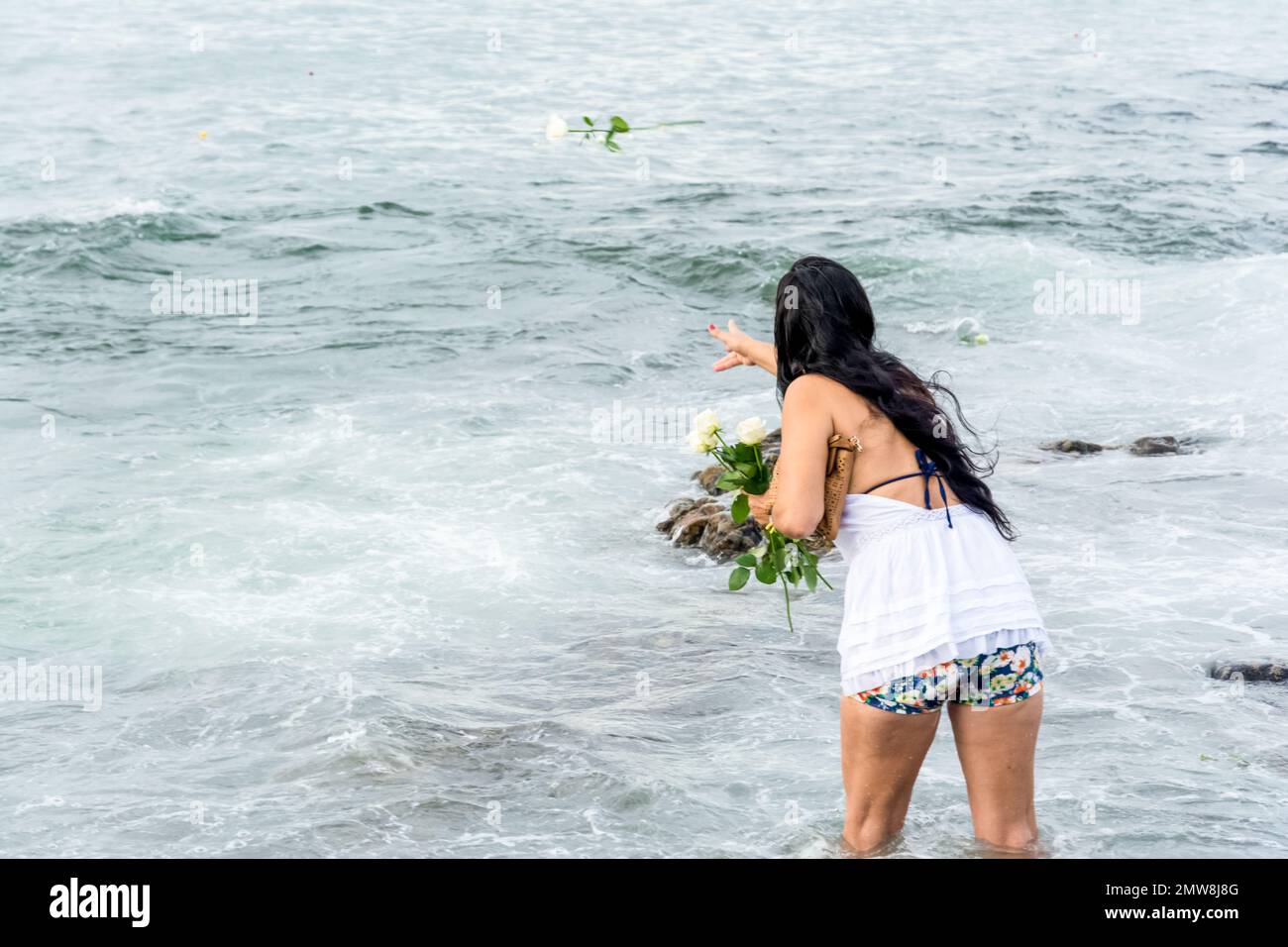 Salvador, Bahia, Brasile - 02 febbraio 2017: Una donna che ammira Candomble getta fiori in mare in onore di Iemanja il giorno della sua festa. Salvador, Foto Stock