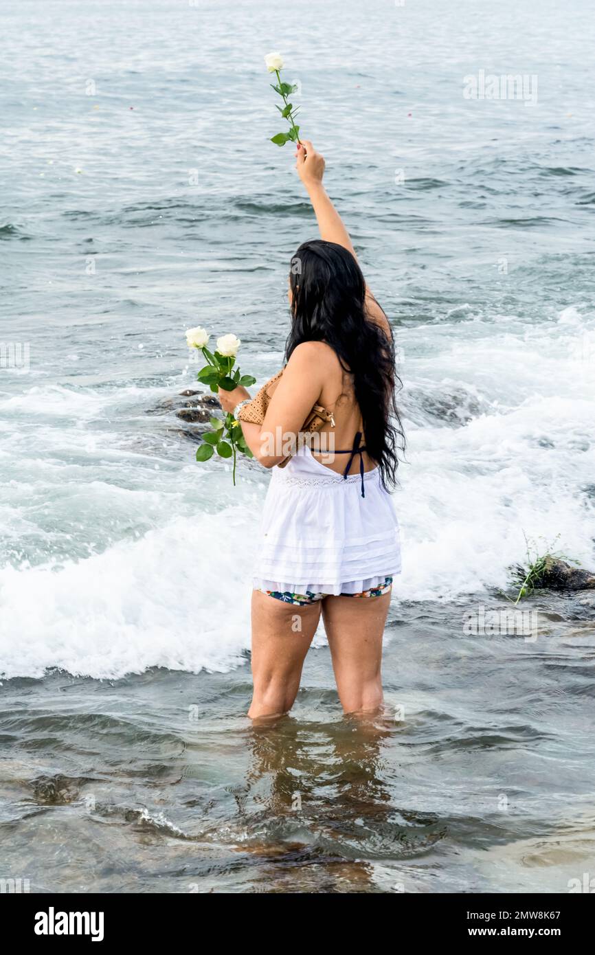 Salvador, Bahia, Brasile - 02 febbraio 2017: Una donna che ammira Candomble getta fiori in mare in onore di Iemanja il giorno della sua festa. Salvador, Foto Stock