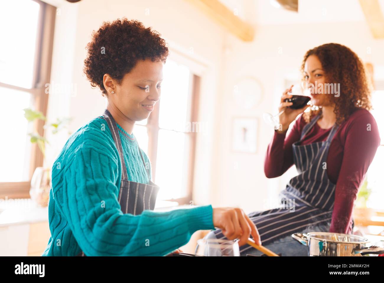 Felice coppia lesbica diversi cucinare insieme e bere vino in cucina Foto Stock