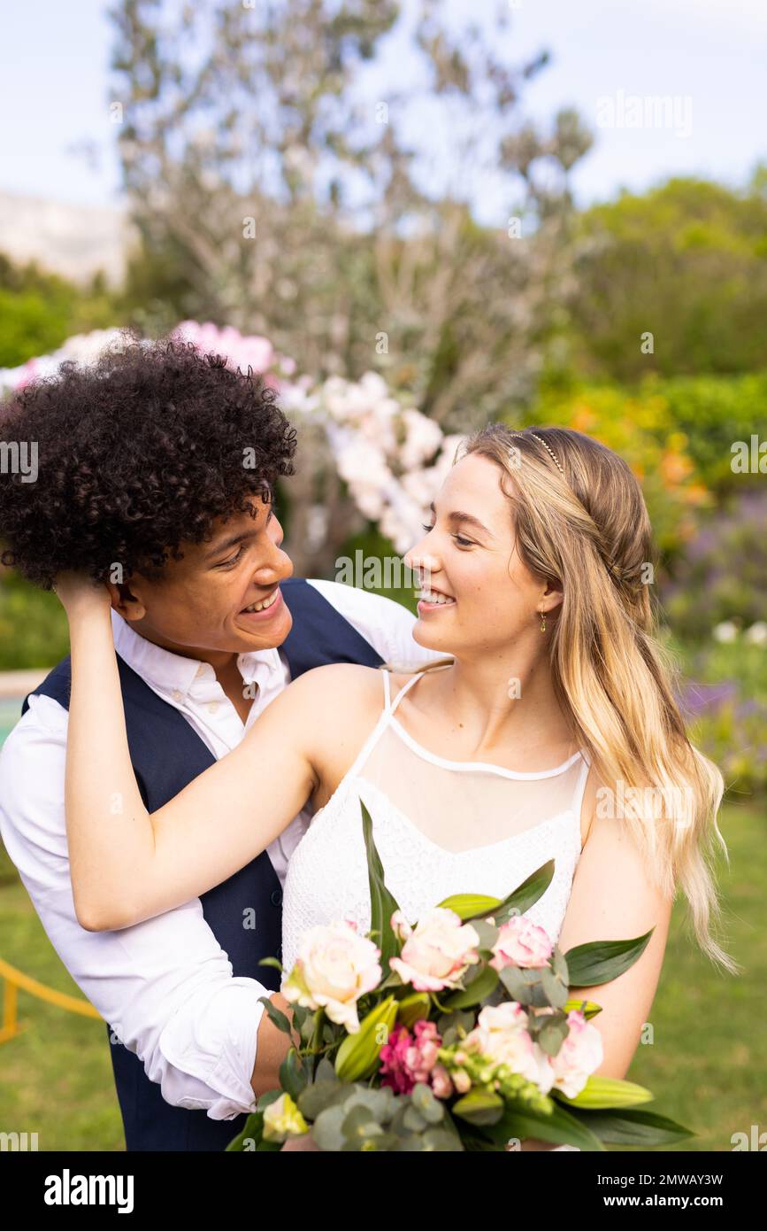 Verticale di spose e sposi diverse e felici con bouquet che abbraccia il matrimonio all'aperto Foto Stock