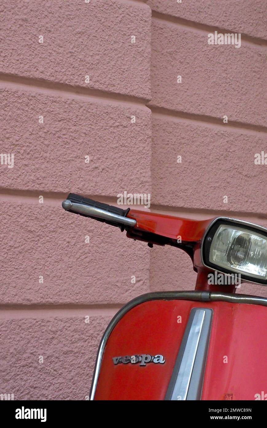 Manubri e parte anteriore di uno scooter rosso davanti a una parete rosa della casa, Vespa, Svizzera Foto Stock