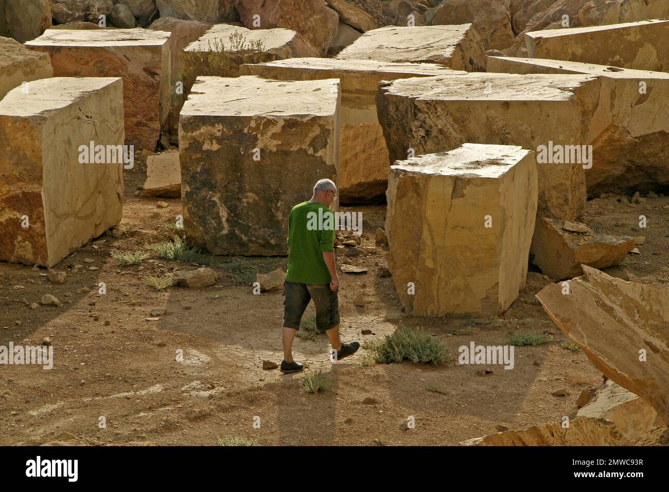 Uomo che cammina di fronte a blocchi di pietra avertina tagliati in cava, Spagna Foto Stock