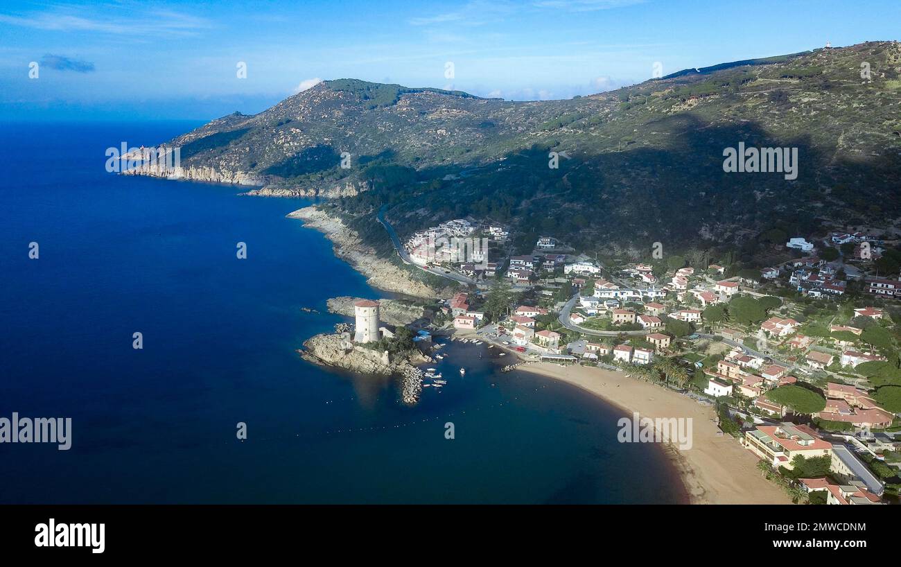 Vista a volo d'uccello della costa del Giglio Campese con la torre di difesa saracena Torre del Campese dal 1600, Giglio Campese, Isola del Giglio, Toscana Foto Stock