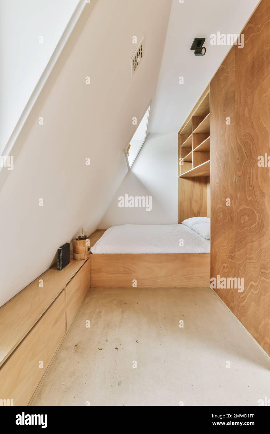 una camera da letto a mansarda con mobili in legno e costruita nelle pareti per renderla simile ad una casa moderna o ad un ufficio Foto Stock
