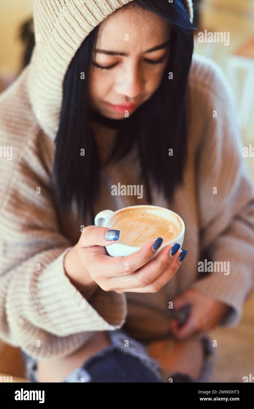 donna caffè con mano che tiene una tazza in caffè, giovane donna bere caffè rilassato donna odore caffè a casa in inverno con caffè da tazza Foto Stock