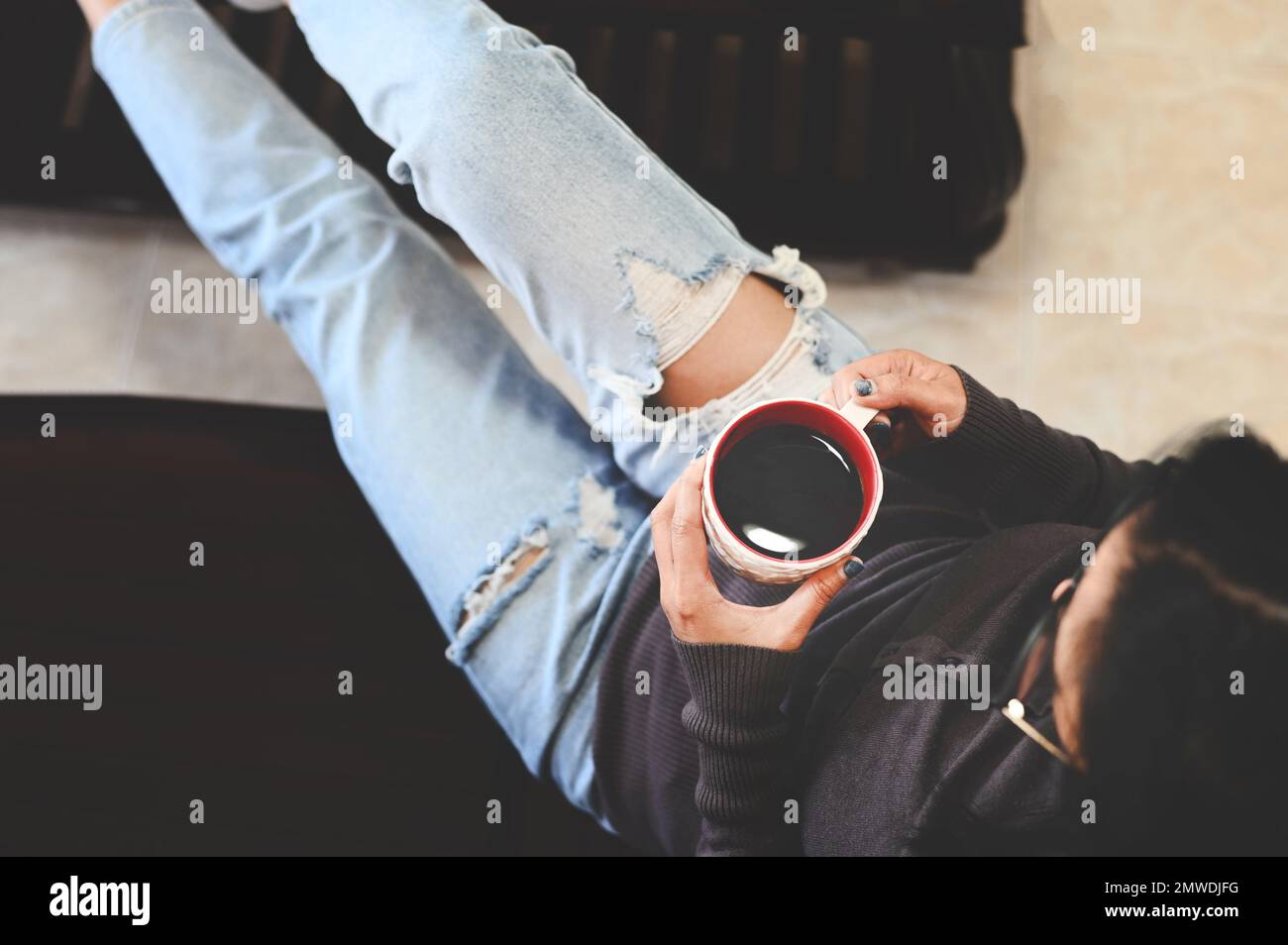 Donna che si rilassa a casa e seduta sul divano e guardando bere caffè, mattina relax ragazza seduta e godendo caffè tempo libero felice donna Foto Stock