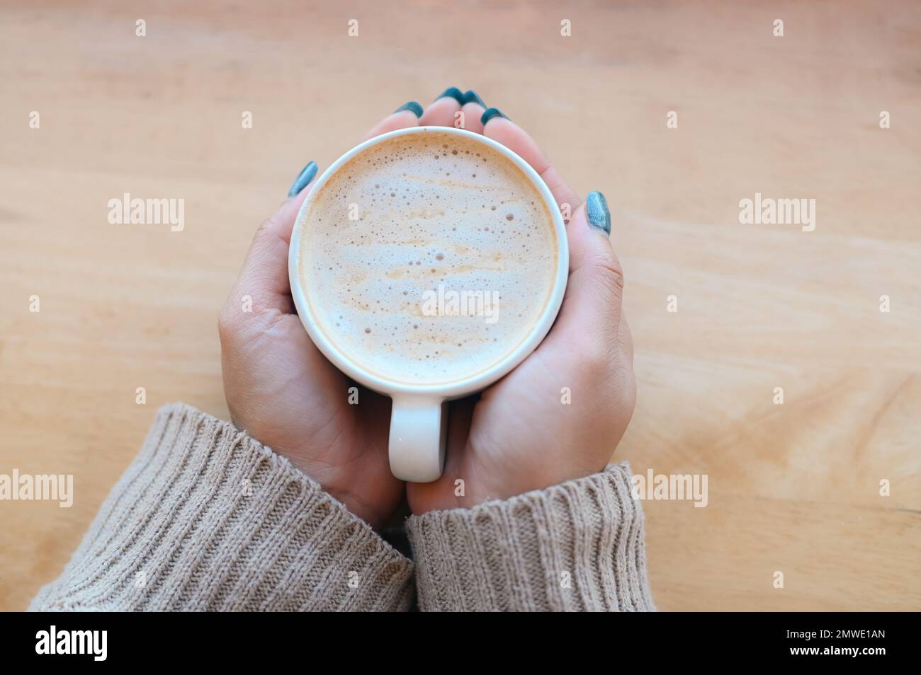 vista dall'alto caffè caramello donna caffè con mano che tiene una tazza sul tavolo di legno, caramello caffè tazza al mattino - caramello caldo macchiato Foto Stock