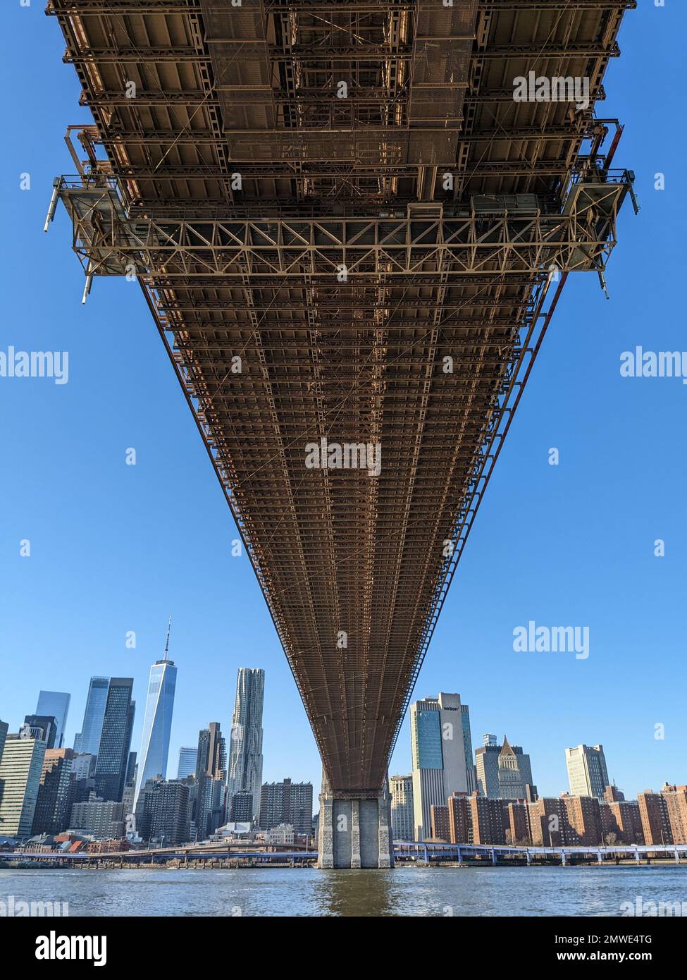 Vista sotto il Ponte di Brooklyn lungo l'East River con lo skyline di Lower Manhattan sullo sfondo. Foto Stock