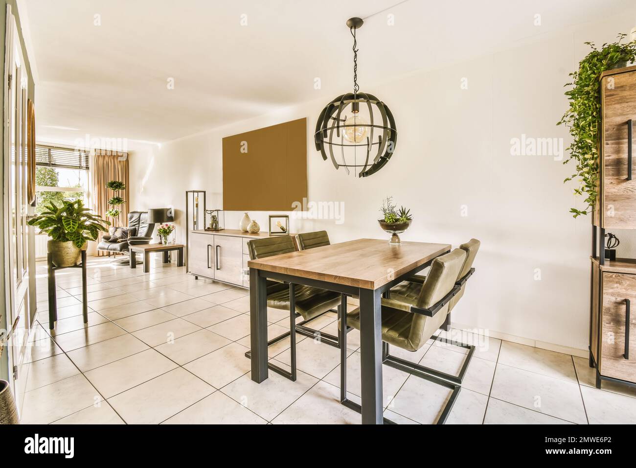 una sala da pranzo con un tavolo, sedie e piante sulla parete di fronte al  soggiorno è pavimento in piastrelle bianche Foto stock - Alamy