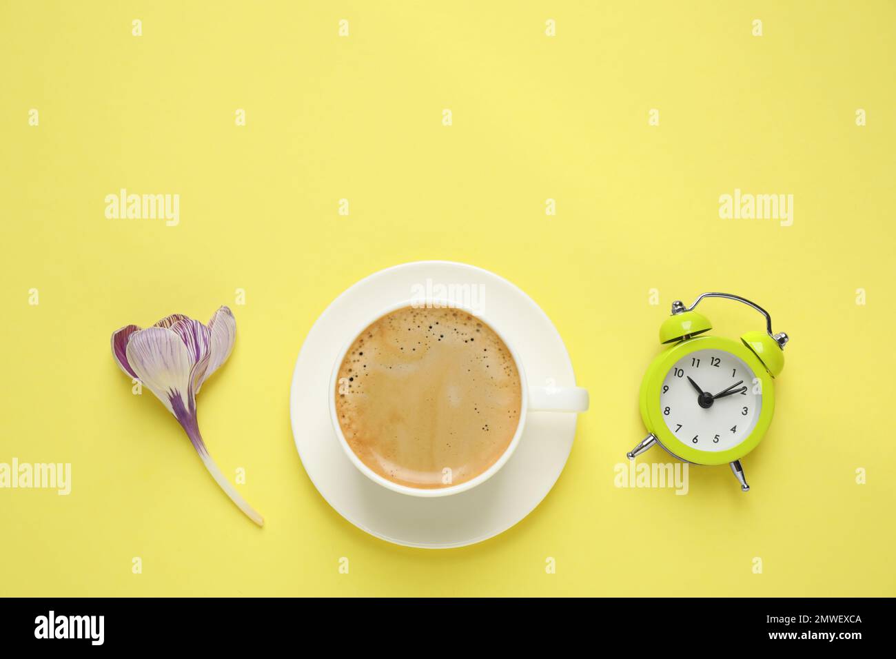 Delizioso caffè del mattino, sveglia e fiore su sfondo giallo, piatto.  Spazio per il testo Foto stock - Alamy