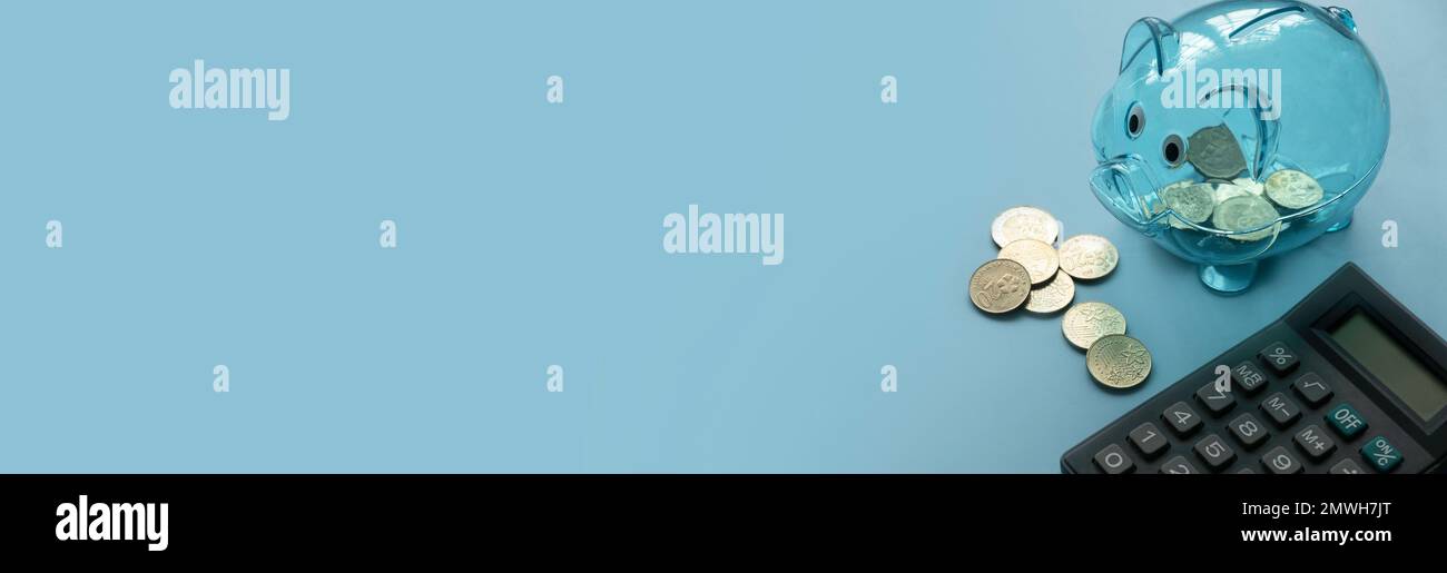 Concetto di business, finanza, investimento, risparmio e finanziamento. Banca di porcellini trasparente, monete e calcolatrice su sfondo blu. Banner con spac copia Foto Stock