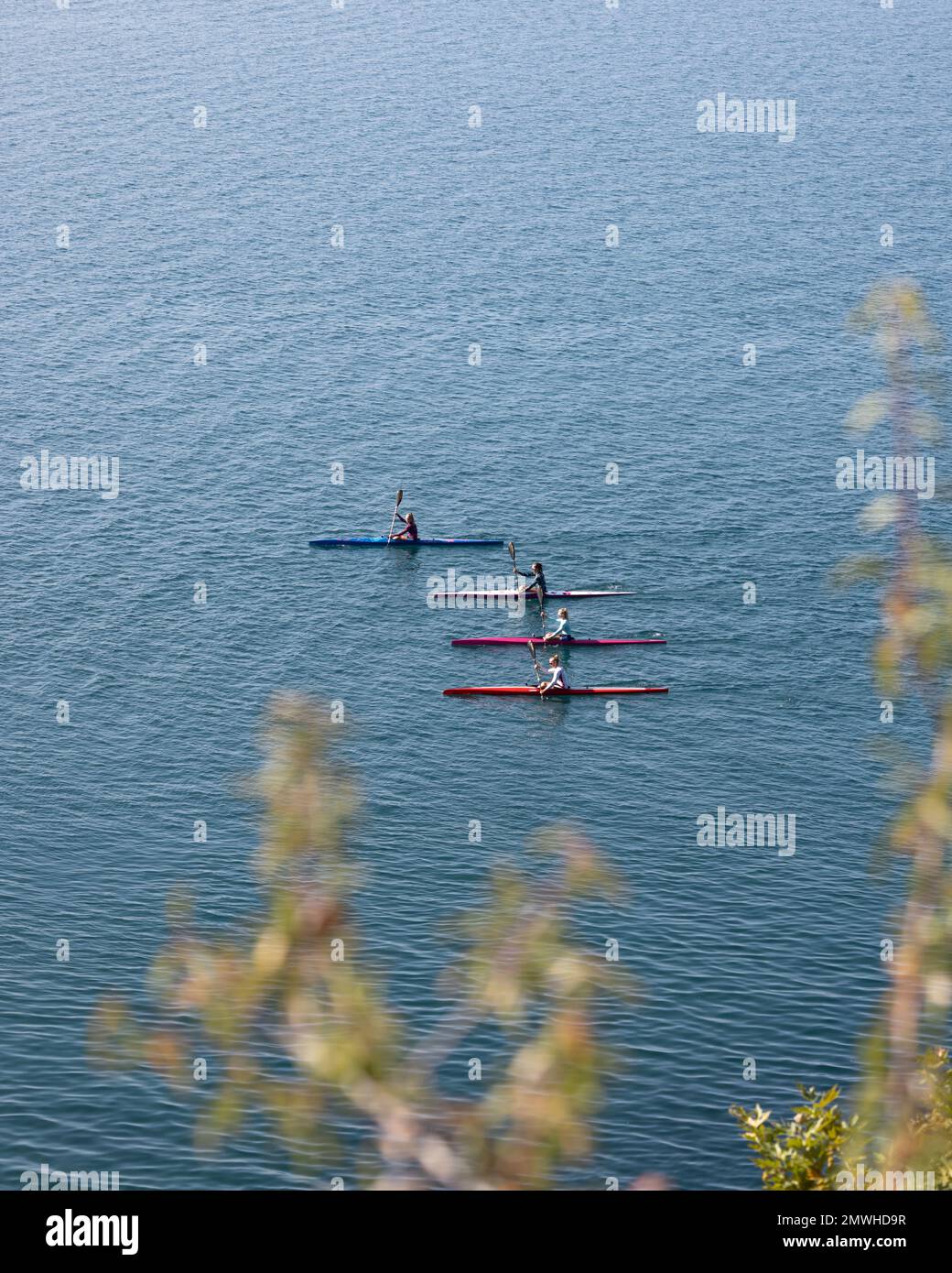 Un gruppo di avventurosi kayakers scivola graziosamente sulle acque tranquille di un pittoresco lago Ohrid. Foto Stock