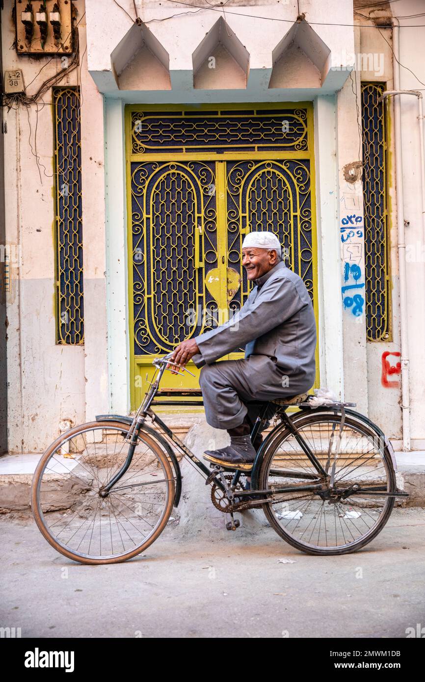 Uomo egiziano in bicicletta lungo le strade di Luxor, Egitto Foto Stock