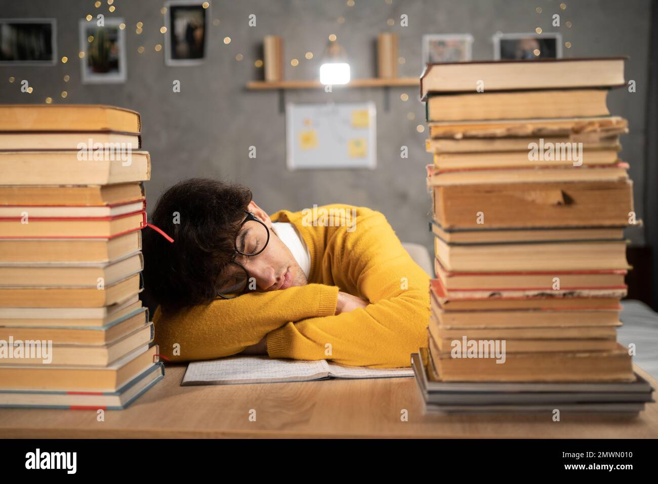 Studente che studia esame duro e dorme tra i libri in biblioteca. Spazio di copia Foto Stock