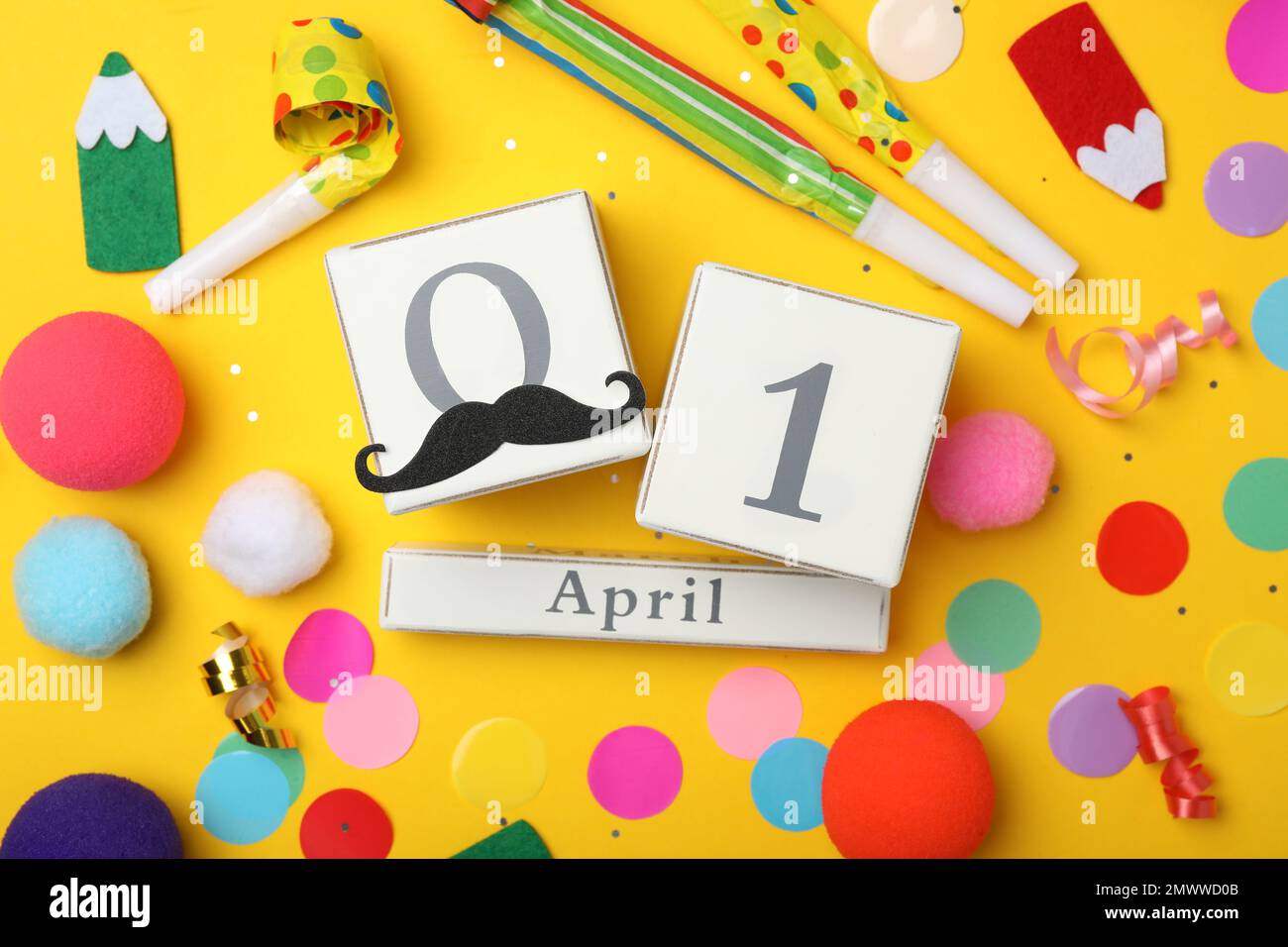 Composizione piatta con calendario a blocchi e elementi per feste su sfondo giallo. Fool's Day di aprile Foto Stock