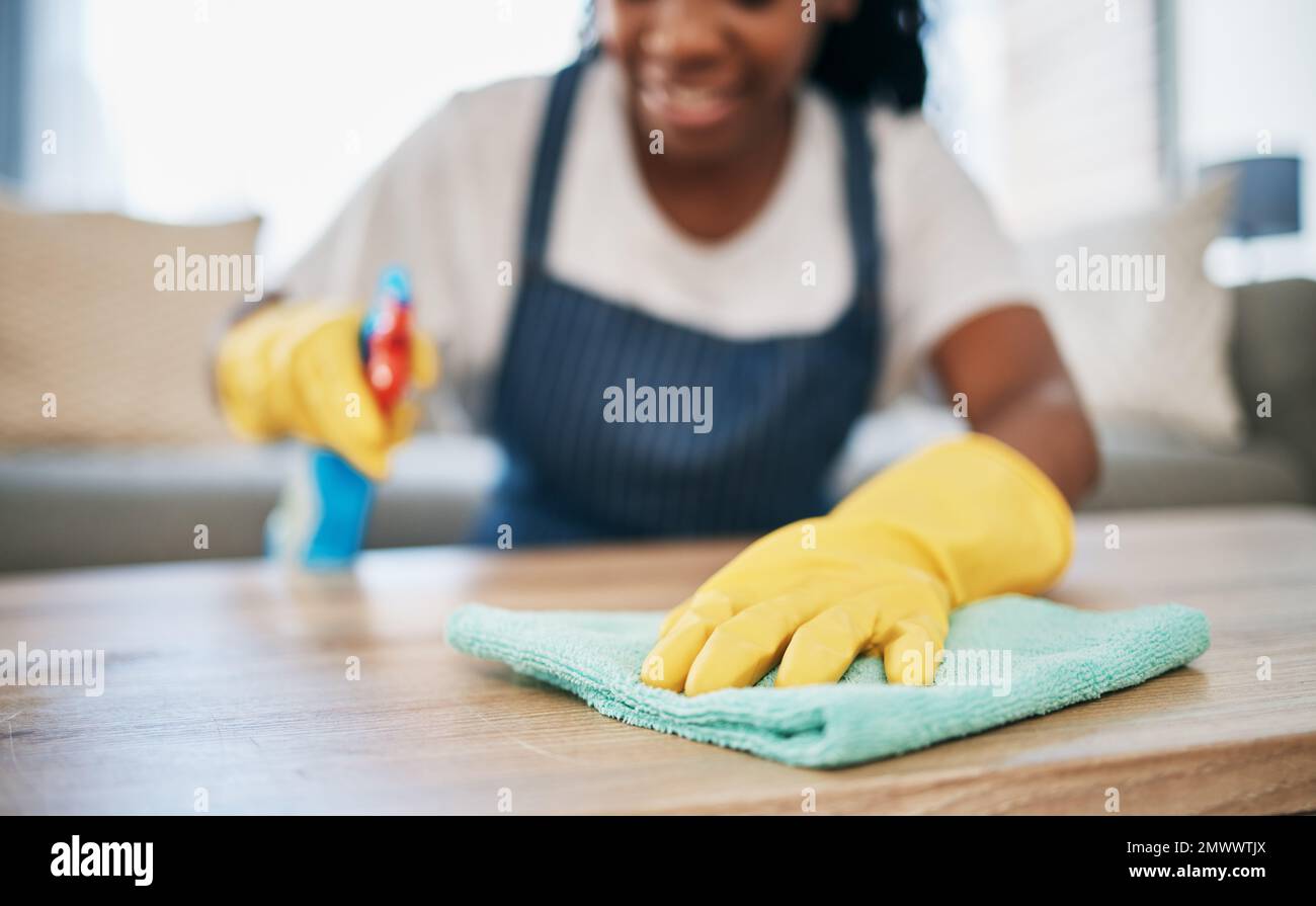 Mano, panno e guanti con una donna nera che pulisce una casa per l'igiene come governante o cameriera. Mobili, batteri e prodotti chimici con un detergente femminile Foto Stock