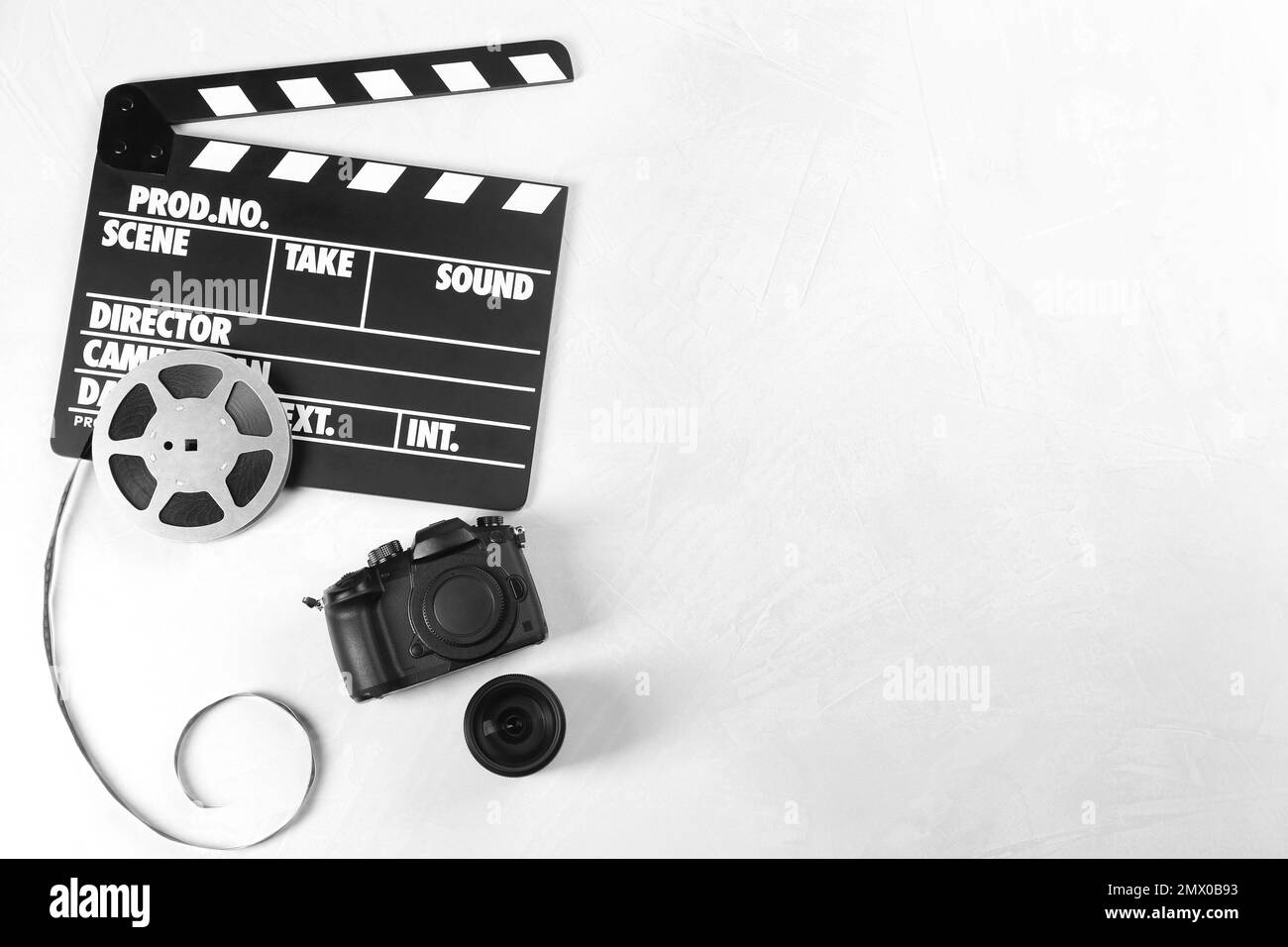 Clapper cinematografico, telecamera moderna e bobina per la produzione di video su un tavolo leggero, piatto. Spazio per il testo Foto Stock