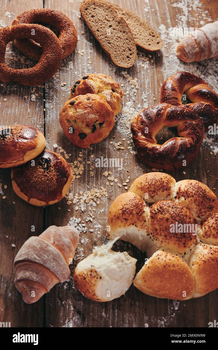 Dall'alto fette di pane turco servite su un tavolo di legno disordinato con vari tipi di dolci in cucina leggera Foto Stock
