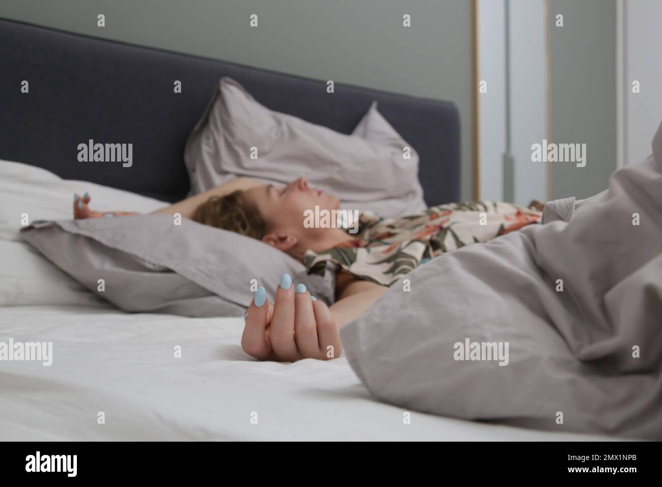 Giovane brunetta tra lenzuola stropicciate in un letto king size Foto Stock