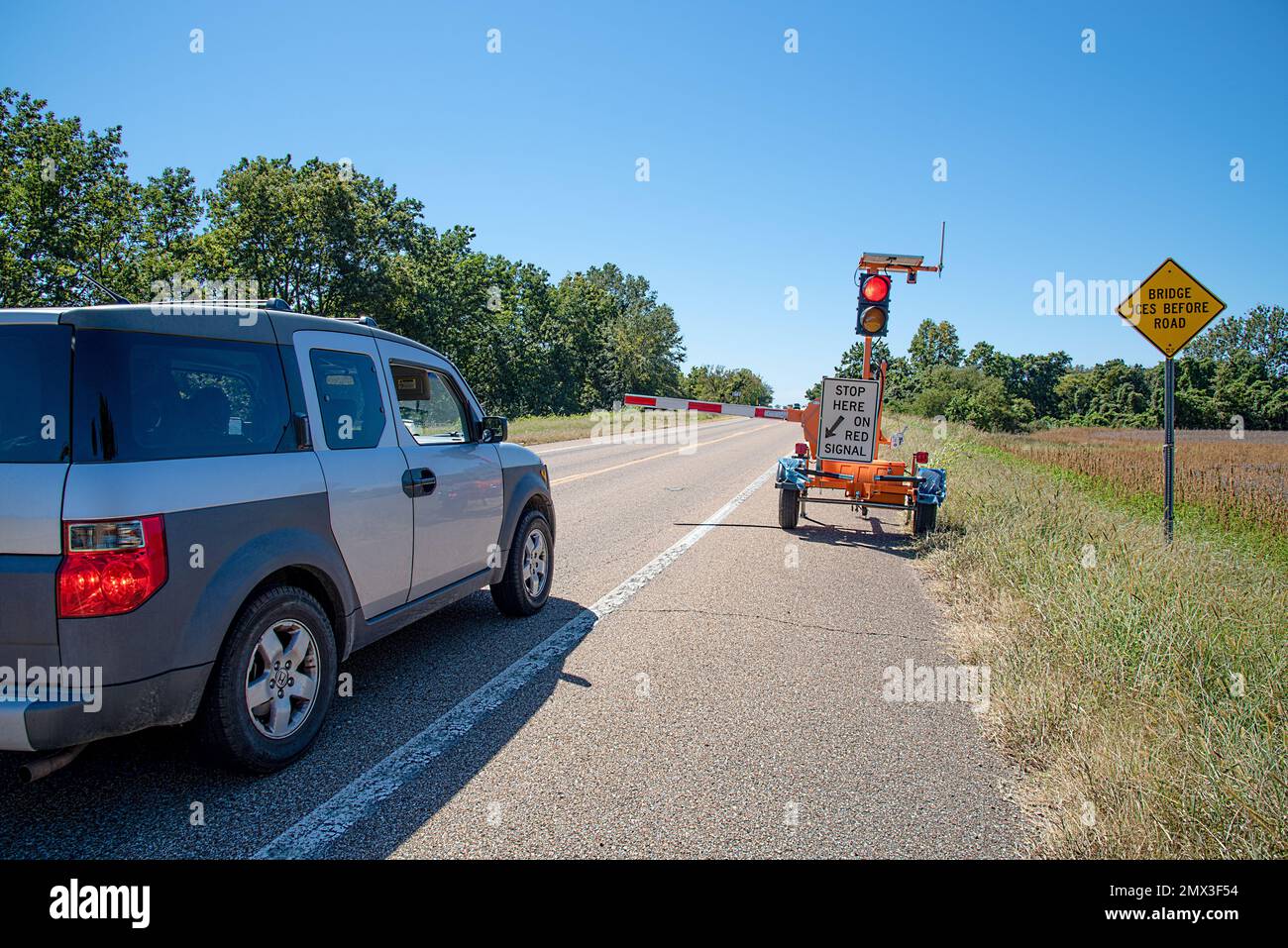 Una vettura, Honda Element, si trova su una tranquilla autostrada a due corsie nel paese fermata da una macchina portatile per il controllo del traffico, con un semaforo rosso. Foto Stock Una vettura, Honda Element, si trova su una tranquilla autostrada a due corsie nel paese fermata da una macchina portatile per il controllo del traffico, con un semaforo rosso. Foto Stock