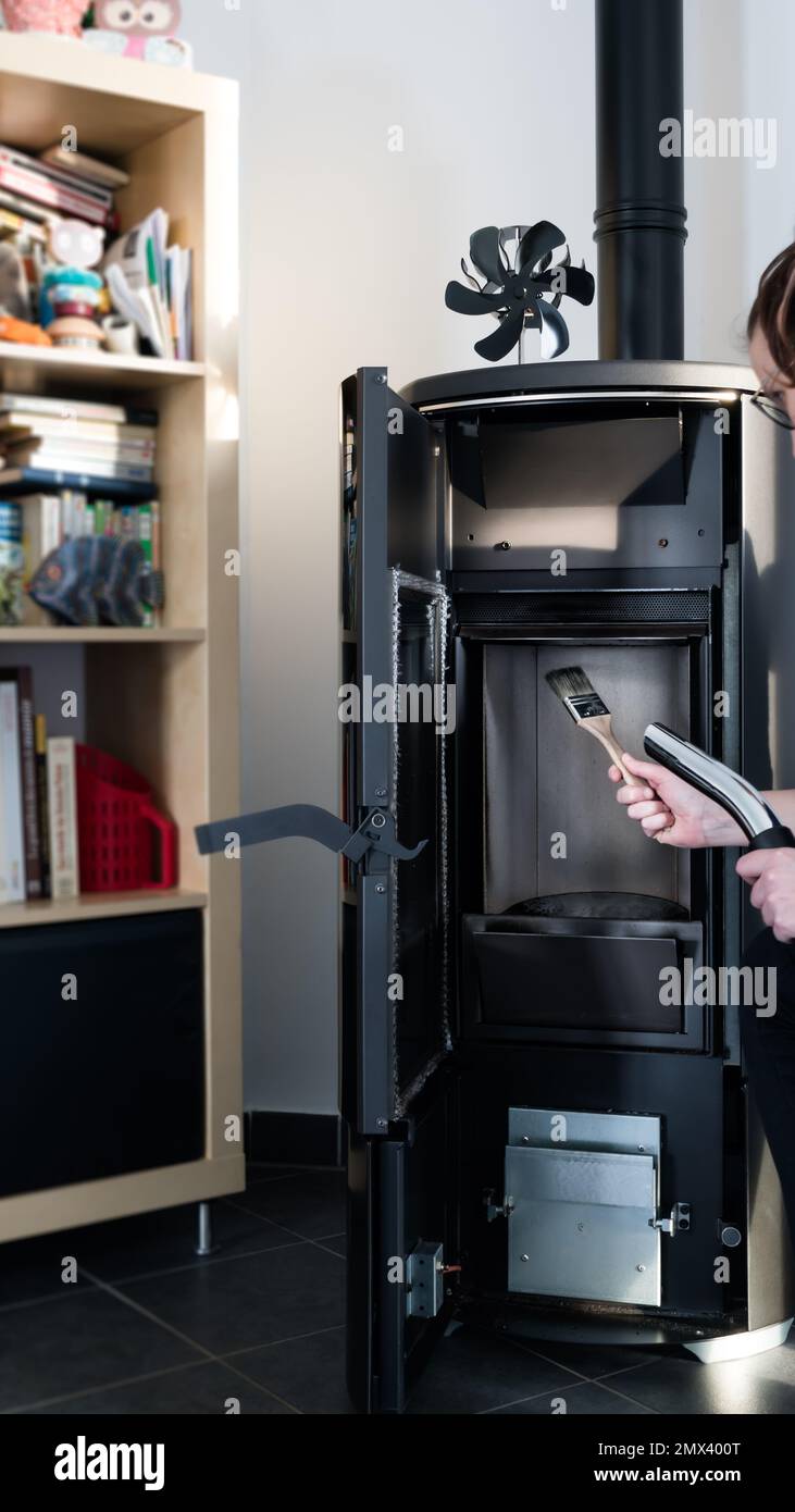 Donna pulizia stufa a pellet con accessori come aspirapolvere o spazzola Foto Stock