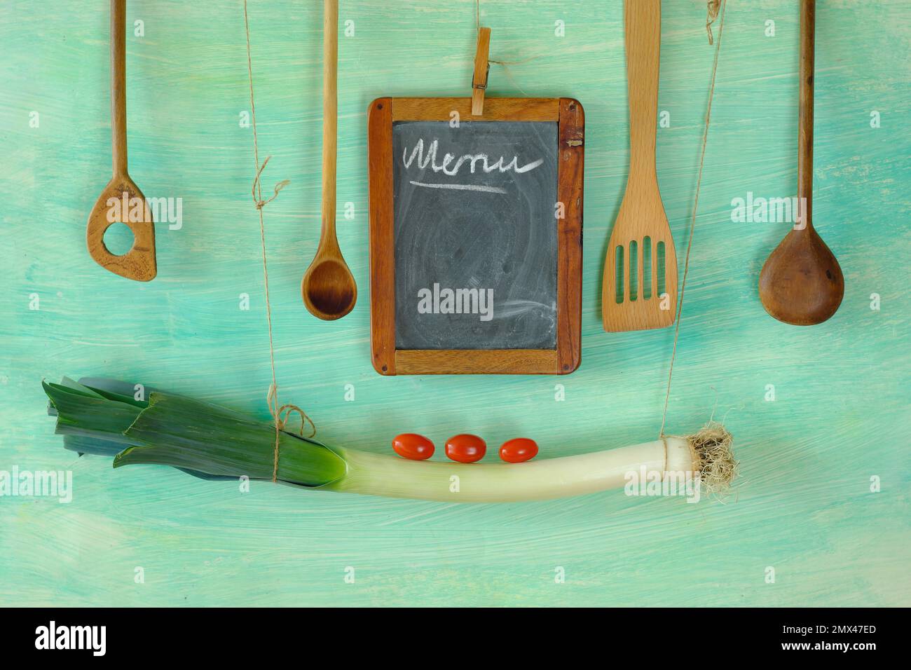 Modello menu con lavagna, porro, pomodori e cucchiai di legno, spazio copia gratuito Foto Stock