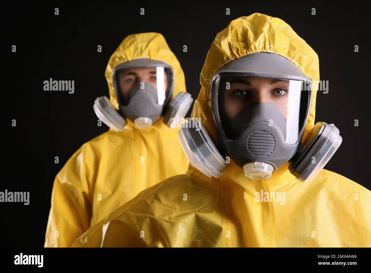 Uomo e donna che indossano tute di protezione chimica su sfondo nero. Ricerca sui virus Foto Stock