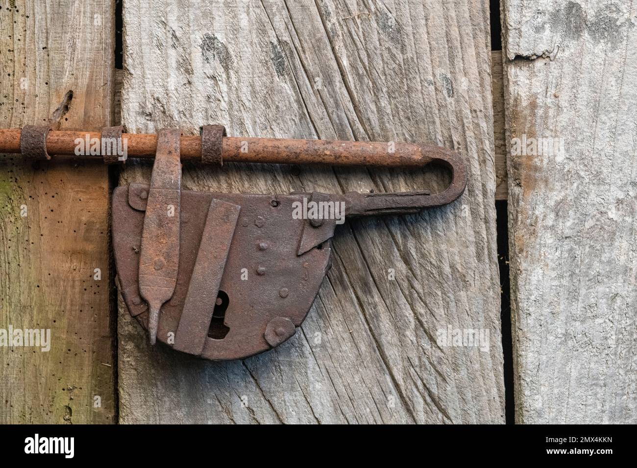 Un vecchio lucchetto e bullone su una porta di un cottage, Sicilia. Probabilmente fatto nel villaggio da un artigiano locale Foto Stock