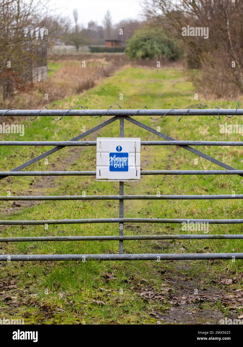 Un cartello 'Keep out' su un cancello metallico che si trova lungo un percorso Foto Stock