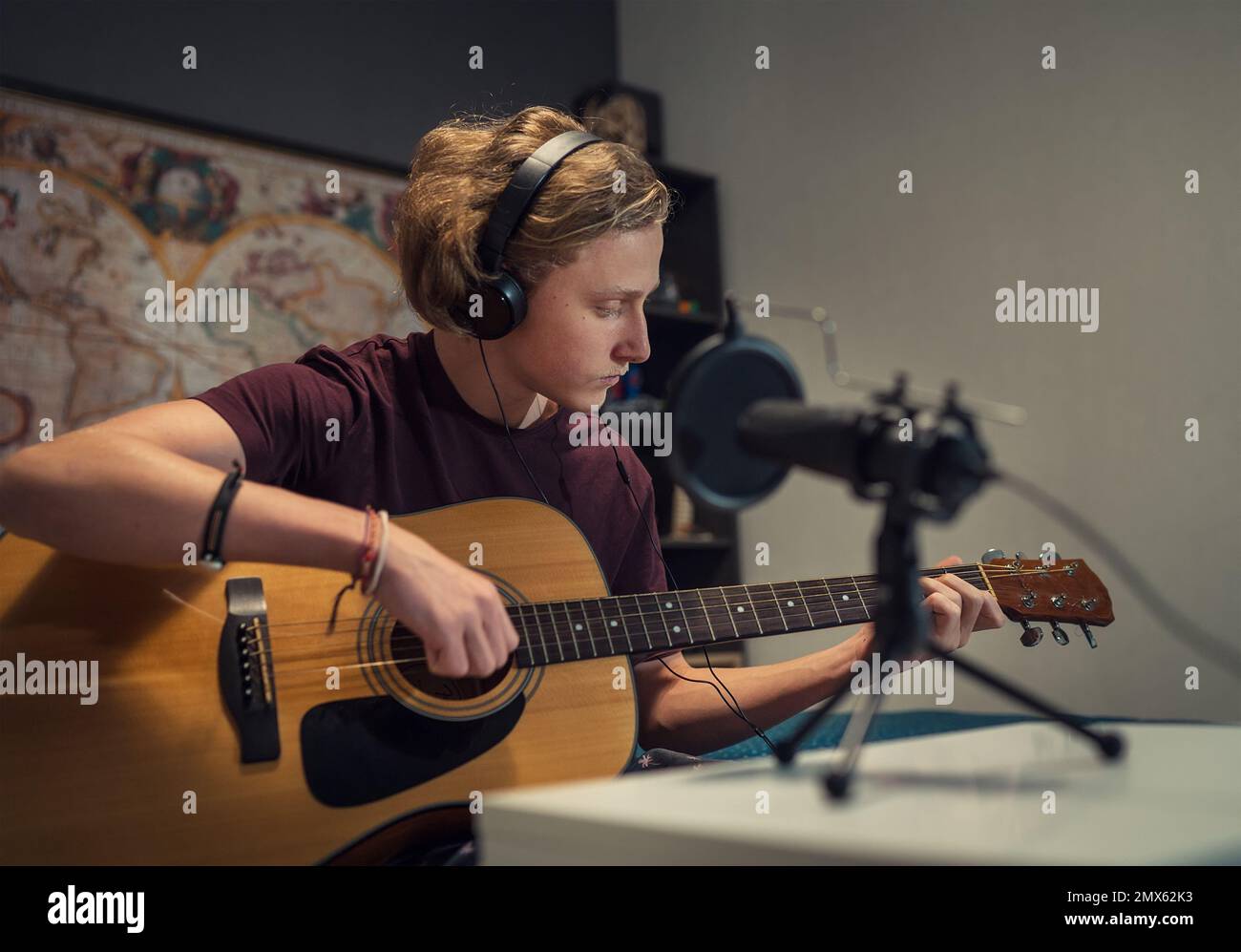 Microfono con filtro pop closeup foto con un ragazzo giovane in cuffie registrazione voce e chitarra suonare musica. Moderno studio di home sound au Foto Stock