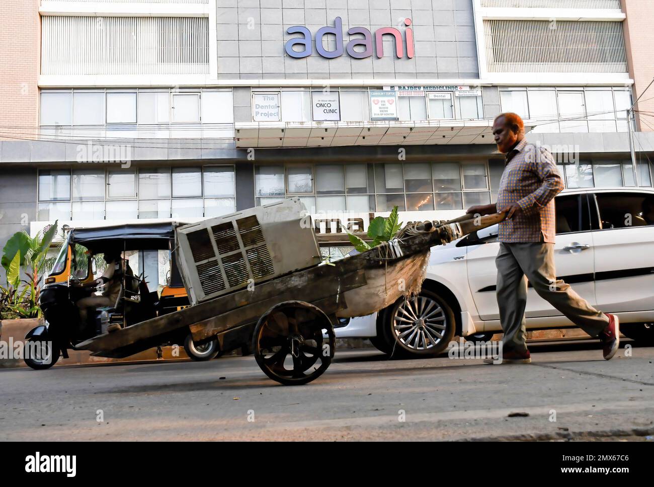 Mumbai, India. 02nd Feb, 2023. Un commerciante di scarto spinge il suo carretto di mano oltre il marchio di Adani su un edificio del deposito a Mumbai. Adani ha annullato la sua offerta pubblica di follow-on (FPO) un giorno dopo che è stata pienamente sottoscritta. In una dichiarazione la società ha dichiarato di avere richiamato l'offerta pubblica di follow-on (FPO) a causa della volatilità del mercato e restituirà il denaro agli investitori. (Foto di Ashish Vaishnav/SOPA Images/Sipa USA) Credit: Sipa USA/Alamy Live News Foto Stock