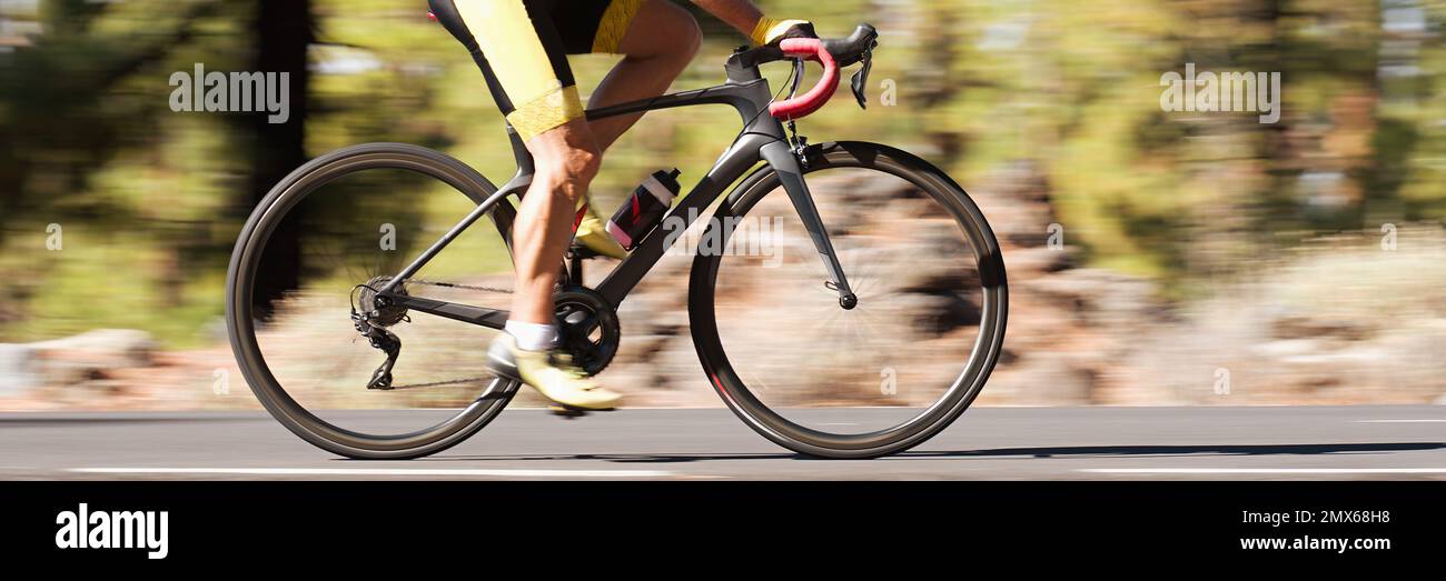 Un ciclista maschile professionista in vestito da corsa durante un giro in bicicletta all'aperto. Tecnica di panning utilizzata Foto Stock