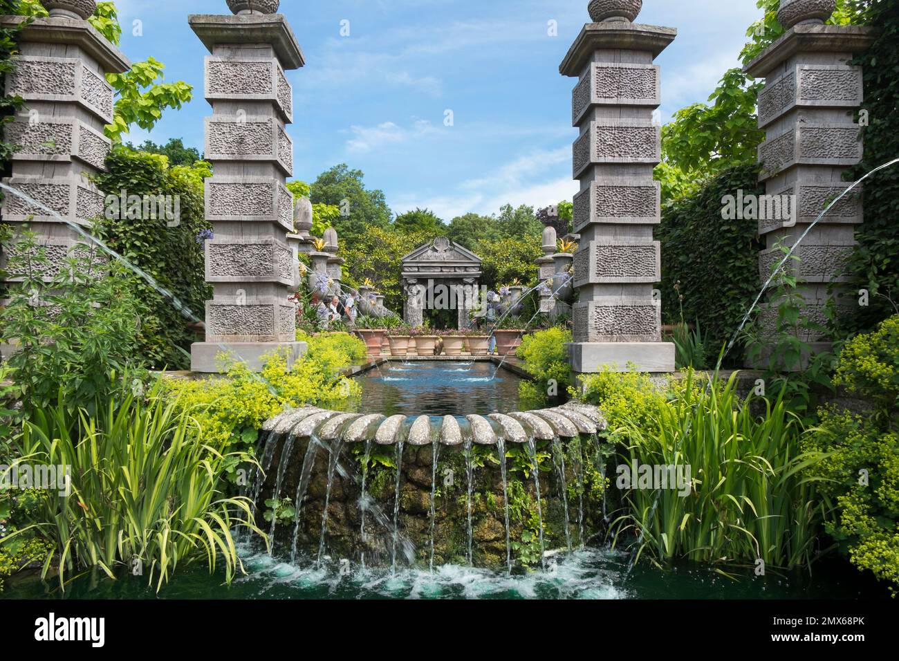 Una piscina con Alchemilla Mollis e una grotta conchiglia Pavillionand acqua che scorre dalle teste dorate dei leoni, Collector Earl's Garden, Arundel Castle, Sussex UK Foto Stock