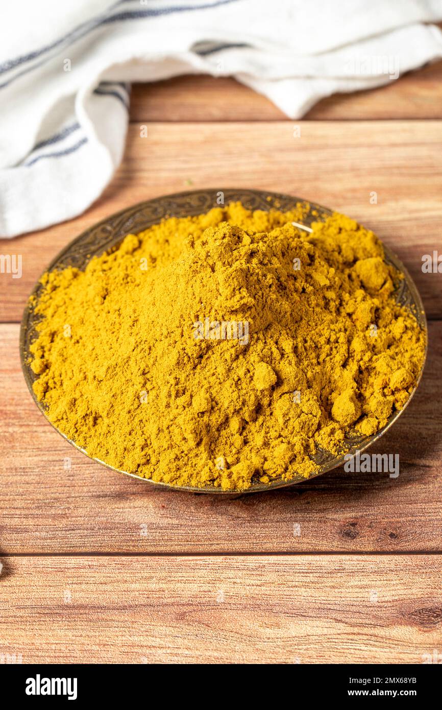 Polvere di Masala al curry. Polvere di curcuma o polvere di curry spezia in una ciotola su fondo di legno. İndian spezie. Concetto di spezie secche. primo piano Foto Stock