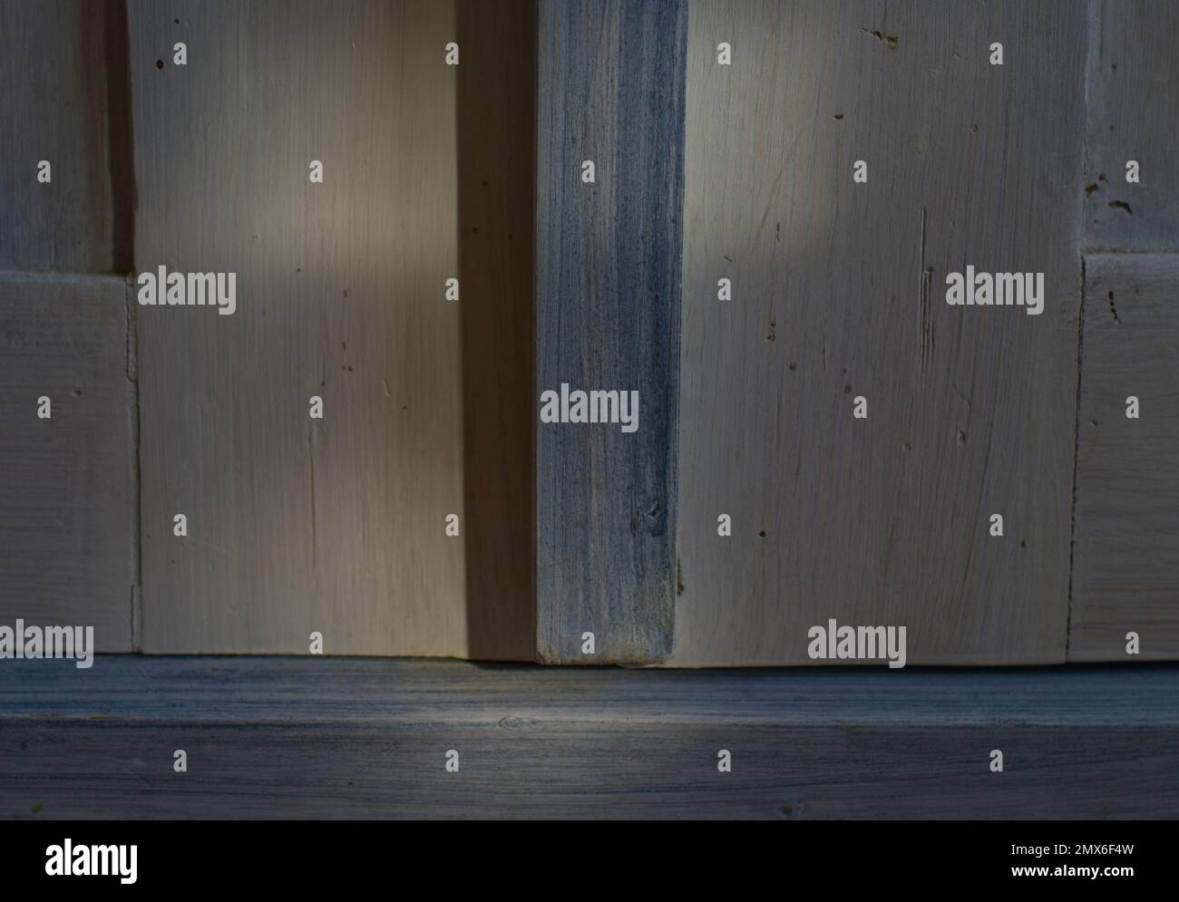 Primo piano di una superficie in legno di un armadio in bianco e blu chiaro con luci e ombre naturali Foto Stock