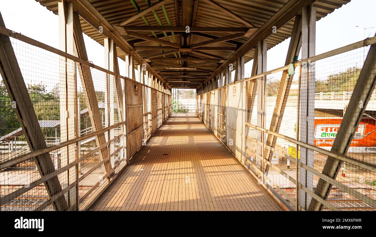 Stazione ferroviaria piede sul ponte, vista interna del corridoio della stazione, piede sul ponte in india ad una stazione ferroviaria rurale, e raggi del sole in arrivo Foto Stock