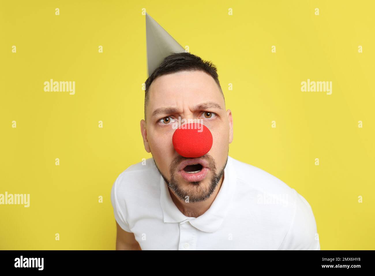 Uomo divertente con naso clown e cappello da festa su sfondo giallo. Aprile  Fool's Day Foto stock - Alamy