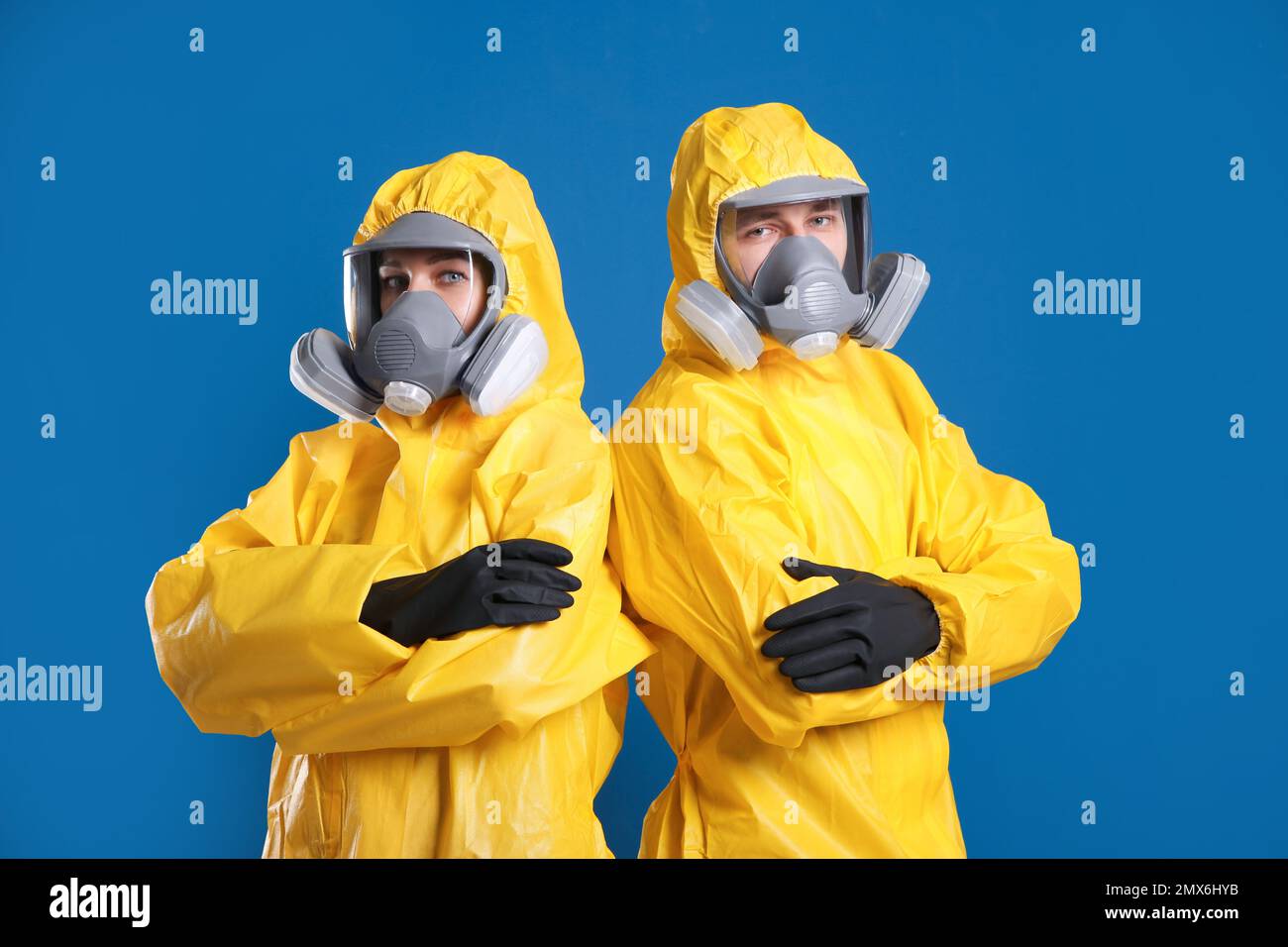 Uomo e donna che indossano tute di protezione chimica su sfondo blu. Ricerca sui virus Foto Stock