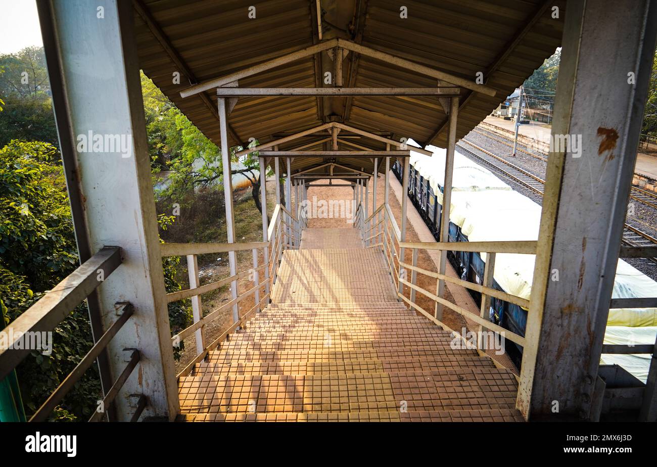 Stazione ferroviaria piede su scala va a piedi su ponte, vista interna del corridoio della stazione, scala di un piede su ponte a una stazione ferroviaria rurale stat Foto Stock