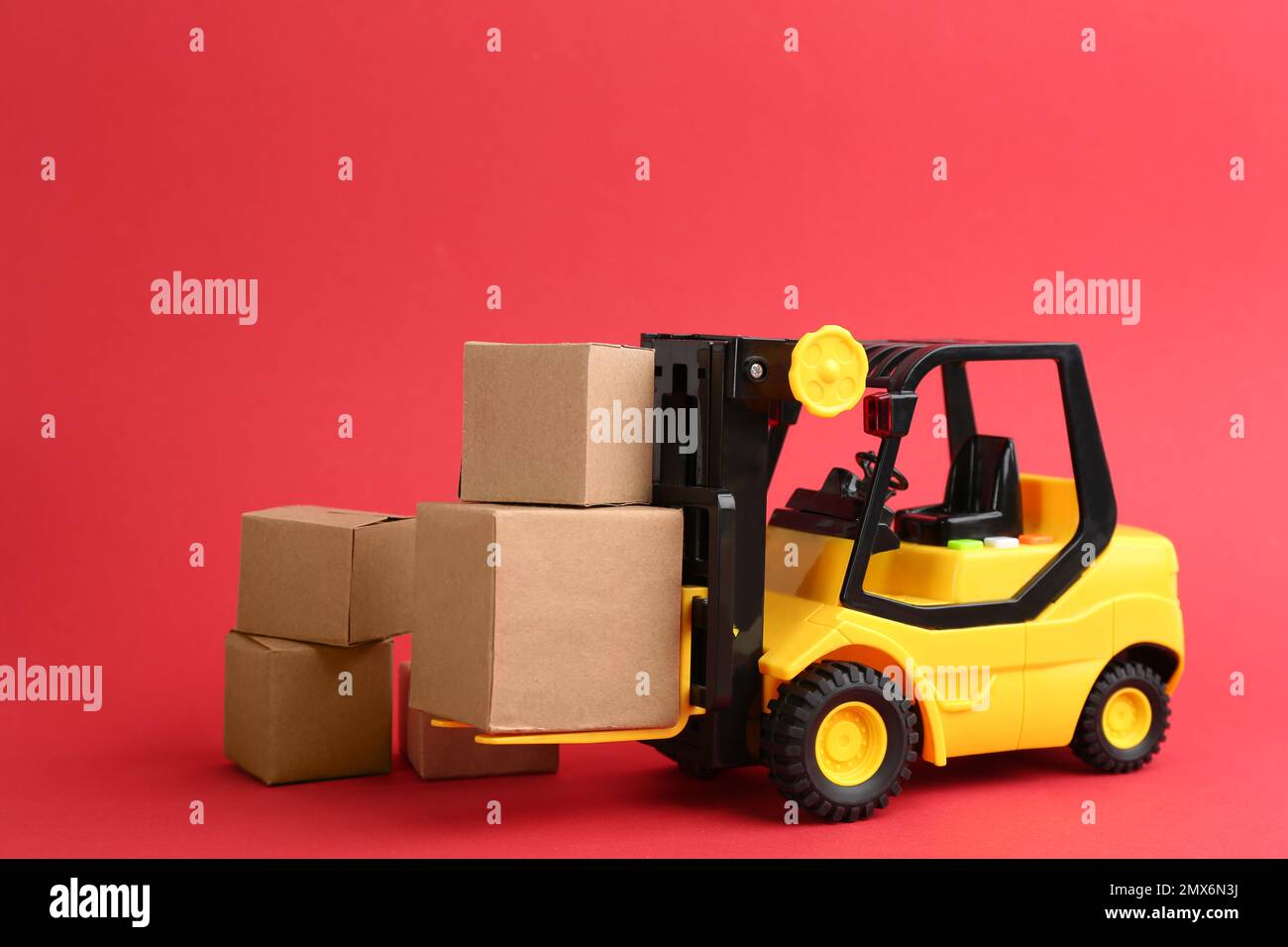 Modello di carrello elevatore e scatole di cartone su sfondo rosso. Servizio di corriere Foto Stock