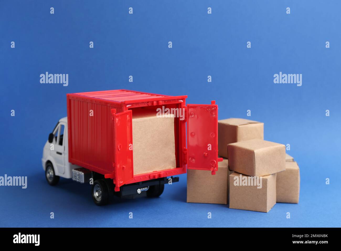 Modello di carrello e scatole di cartone su sfondo blu. Servizio di corriere Foto Stock