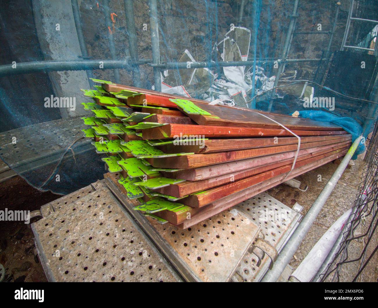 Elementi di ponteggi in legno impilati nel cantiere della città vecchia. Spruzzare la vernice marcata su di essi. Foto Stock