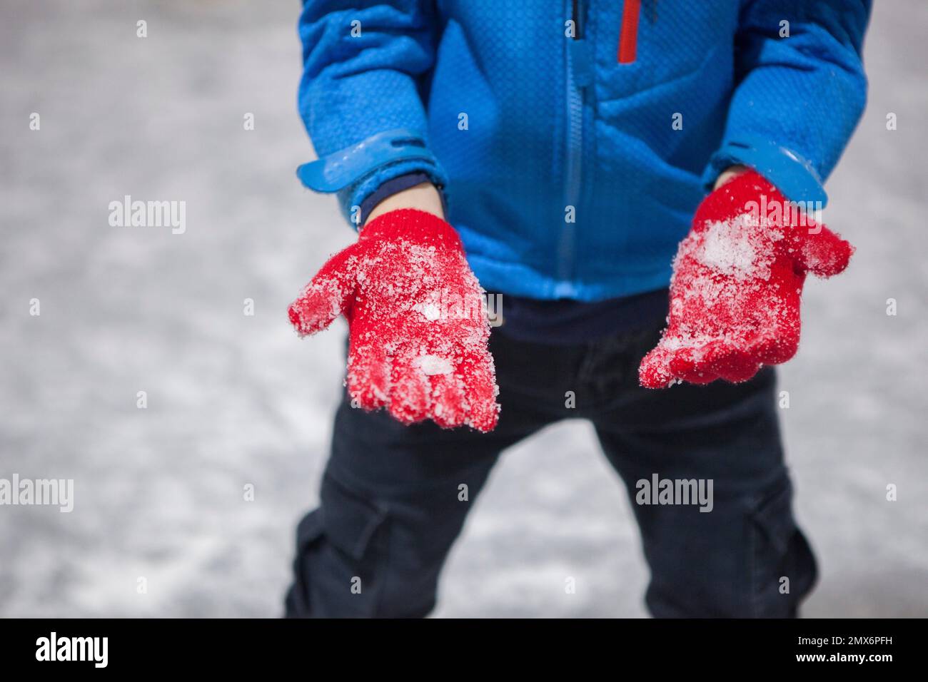 Bambino ragazzo mostrare i suoi guanti pieni di ghiaccio. Concetto di pista di ghiaccio ricreativo. Foto Stock