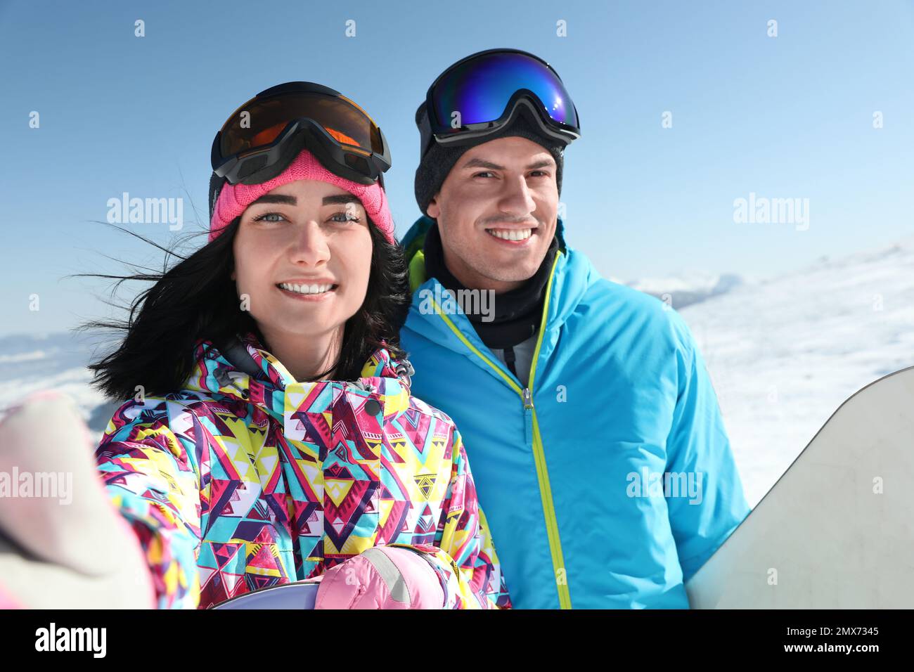 Felice coppia con snowboard in montagna. Vacanze invernali Foto Stock