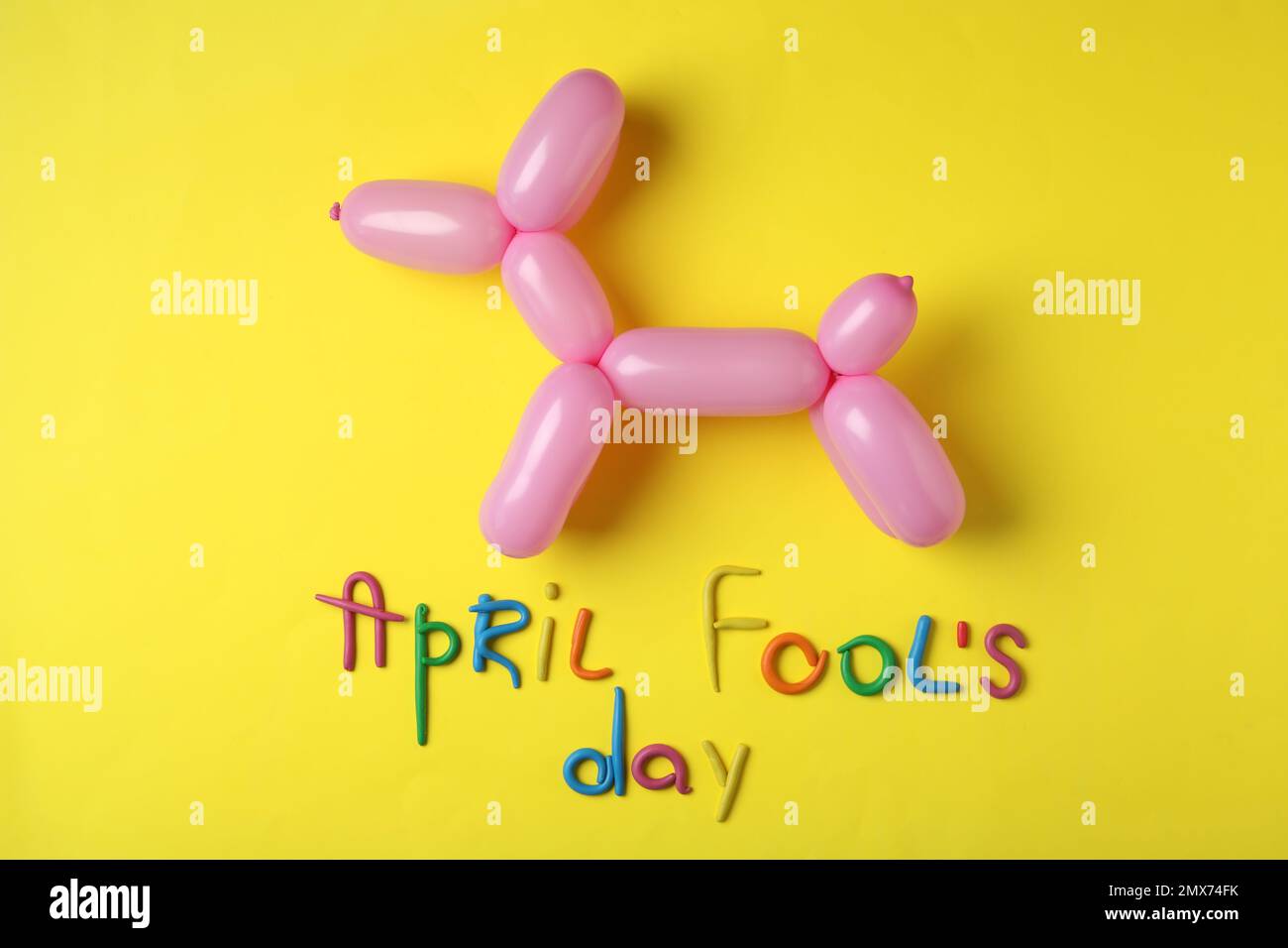 Animale palloncino e frase FOOL's DAY APRILE su sfondo giallo, piatto giacitura Foto Stock