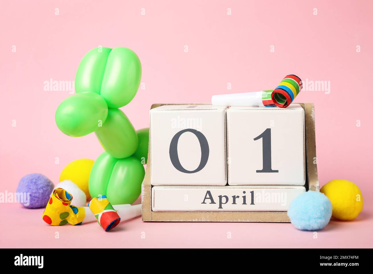 Calendario in legno e decorazioni per feste su sfondo rosa. Aprile Fool's Day Foto Stock